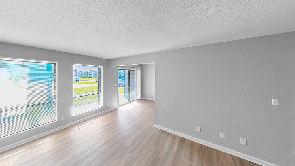 the living room and dining room of an empty house with wood flooring and windows