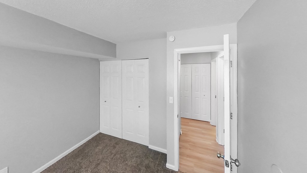 the living room of an apartment with white walls and wood floors
