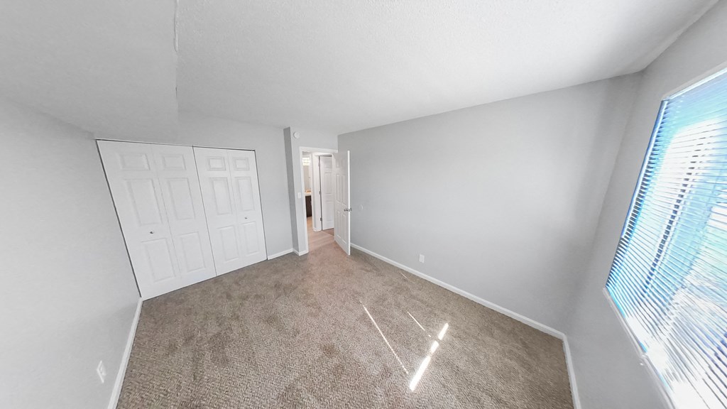 a bedroom with a carpeted floor and a door to a closet