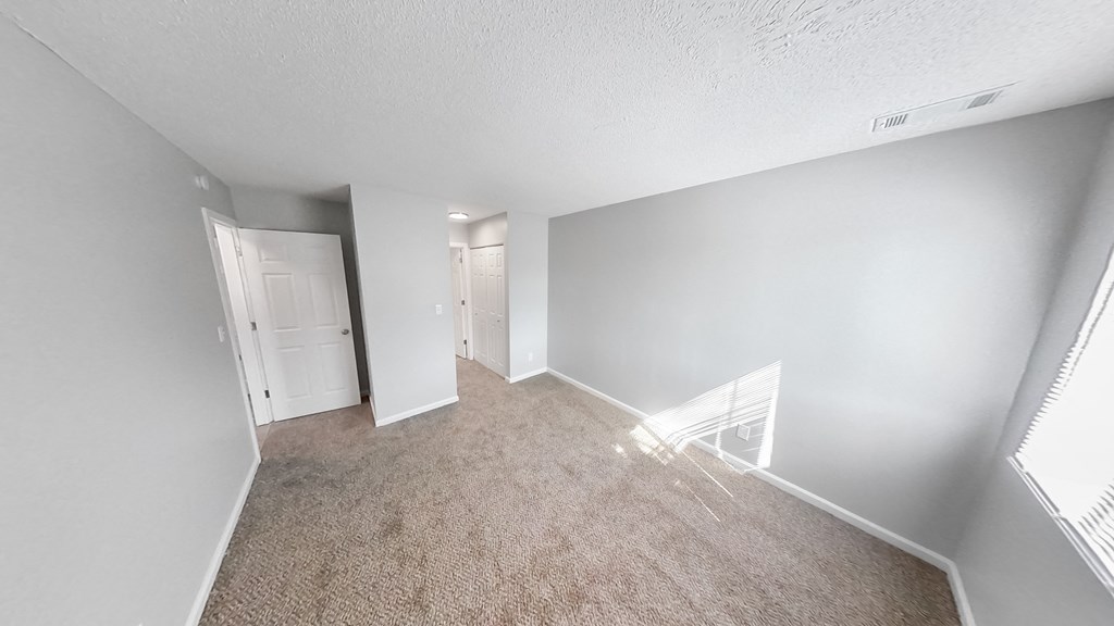 the living room of an apartment with a carpeted floor and white walls