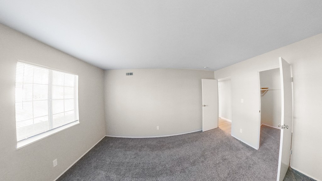 an empty bedroom with a large window and a closet