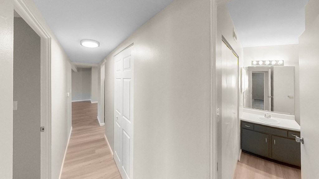 a corridor with a sink and a mirror in a house