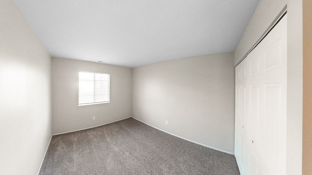 an empty bedroom with white walls and a window