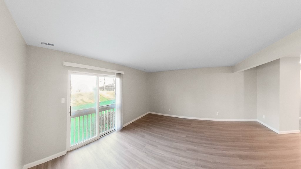 an empty living room with a balcony and wood flooring