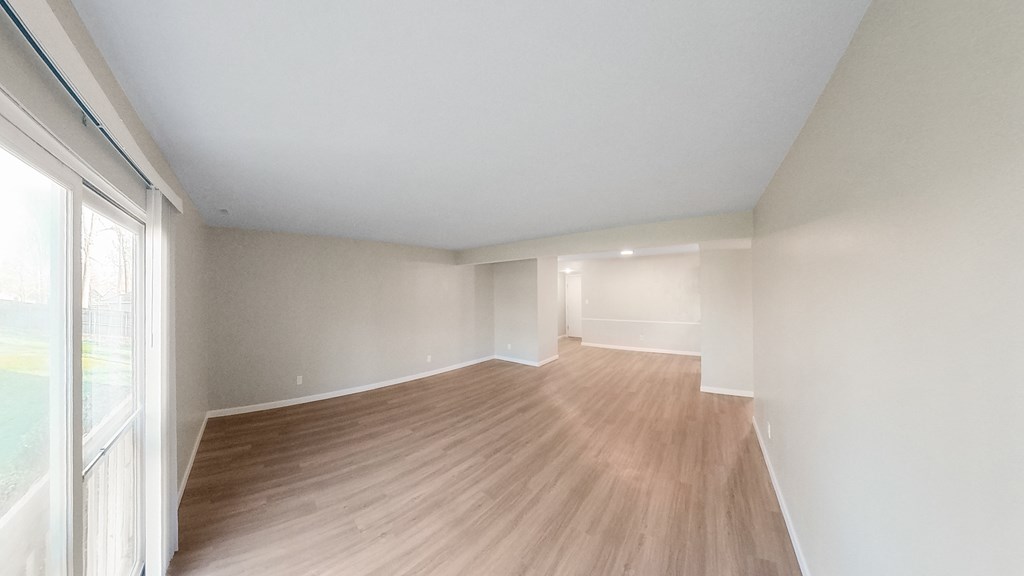 an empty living room with wood flooring and a large window