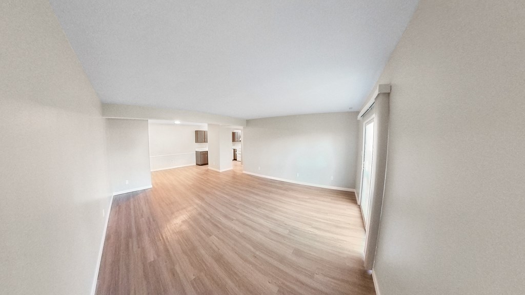 an empty living room with wood flooring and white walls