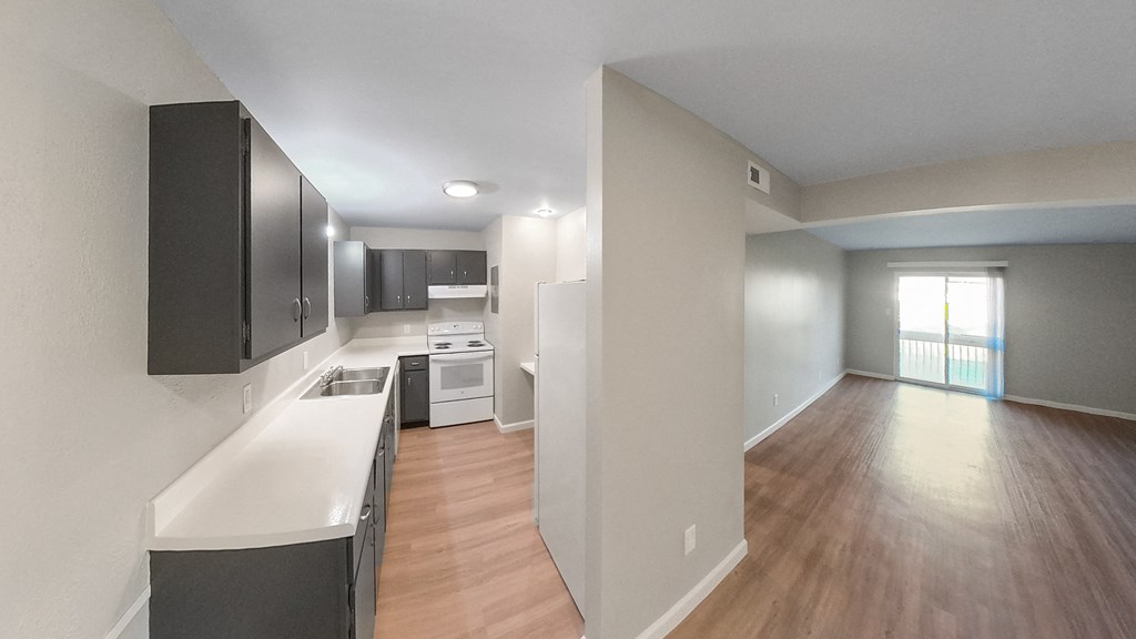 an empty kitchen and living room with wood flooring and a window