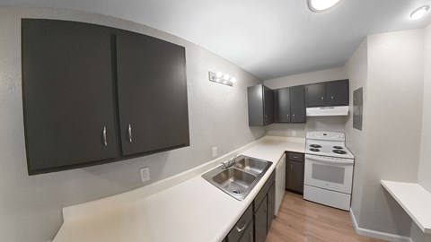 an empty kitchen with black cabinets and white appliances