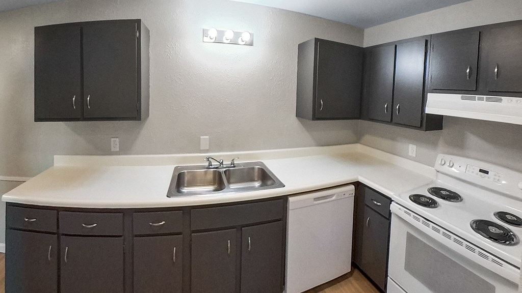 an empty kitchen with black cabinets and white appliances