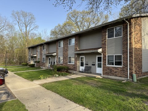 A residential building with a grey facade and a white door.