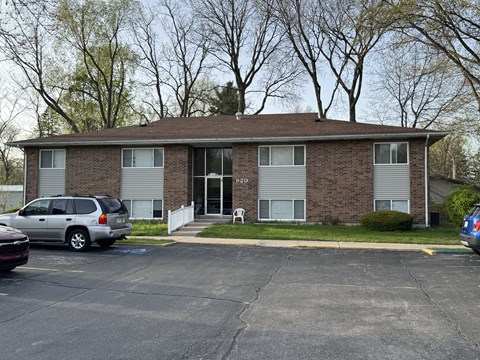 A small brick building with a parking lot in front.