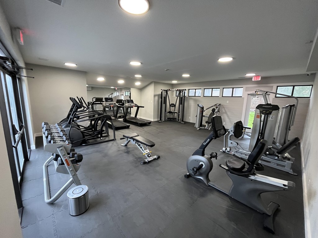 A gym with a variety of equipment including treadmills, weights, and exercise machines.