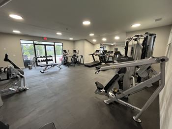 A gym with a variety of exercise equipment including treadmills, stationary bikes, and weight machines.