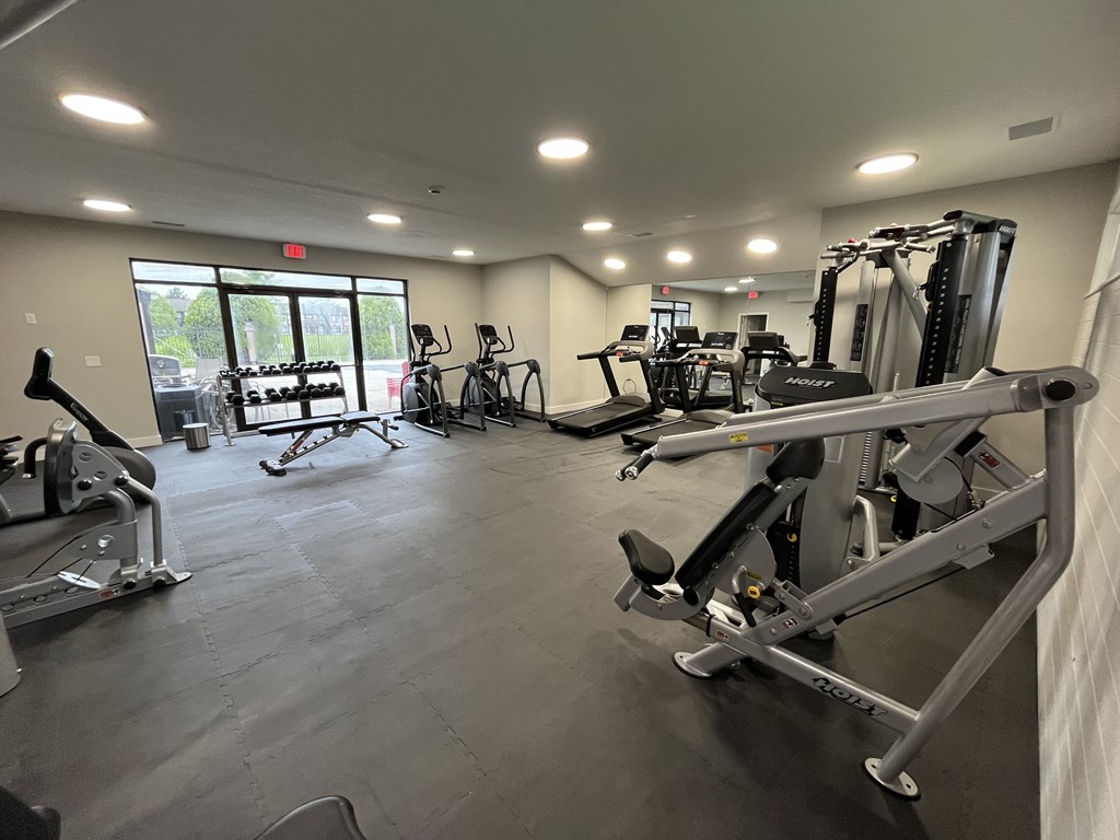 A gym with a variety of exercise equipment including treadmills, stationary bikes, and weight machines.
