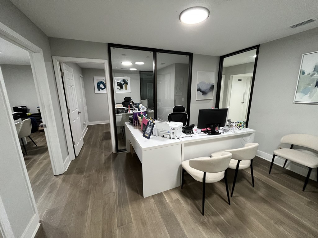 A room with a desk and chairs with a mirror on the wall.