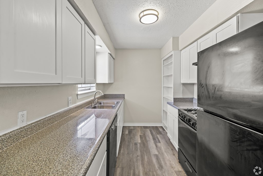 A modern kitchen with a black oven and a granite counter top. at La Bella Apartments, Fort Worth, TX