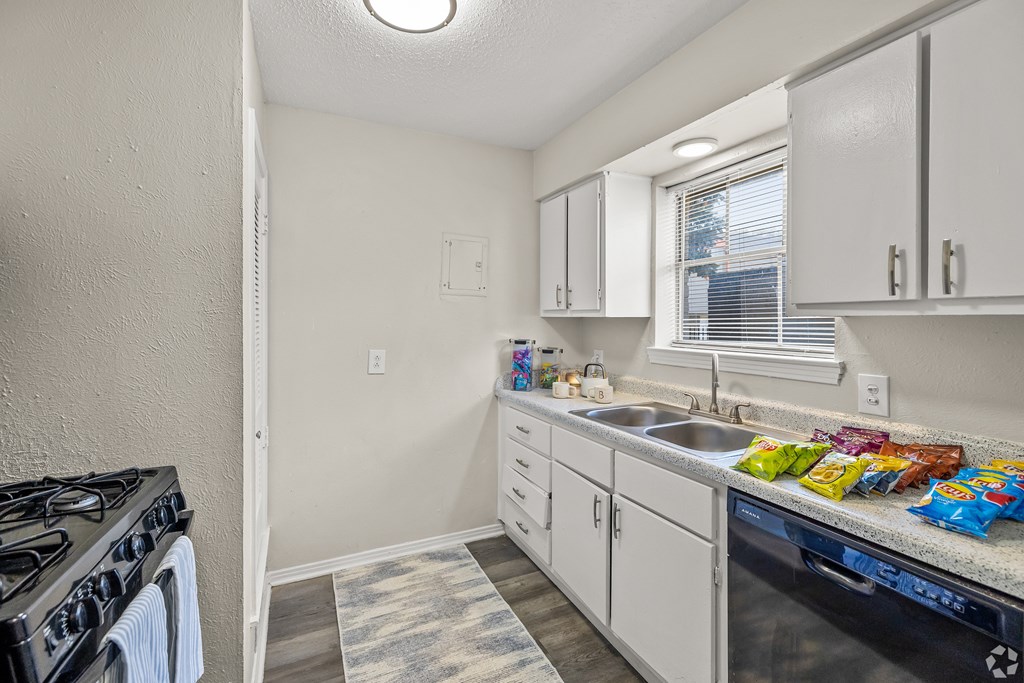 A kitchen with white cabinets and a black stove top oven. at La Bella Apartments, Fort Worth, TX