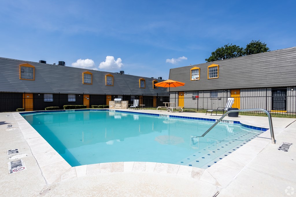 A large outdoor swimming pool with a sun lounger. at La Bella Apartments, Fort Worth, Texas