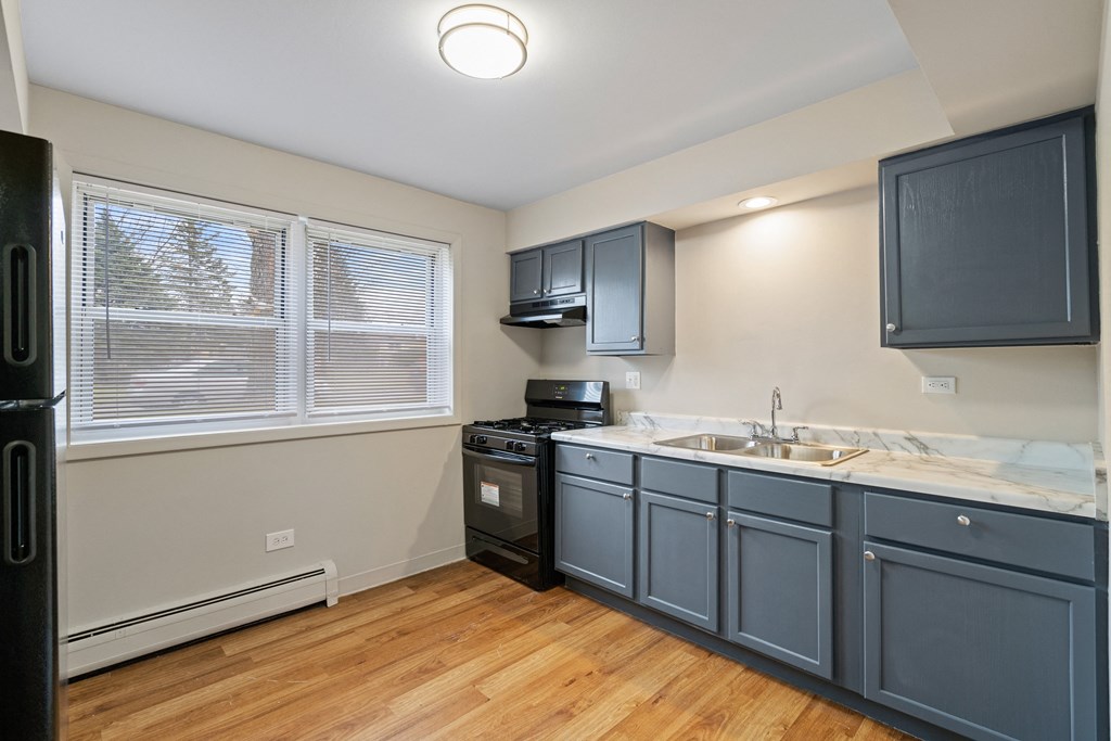 a kitchen with blue cabinets and a sink and a window at Hanover Park Blu Apartments, Illinois