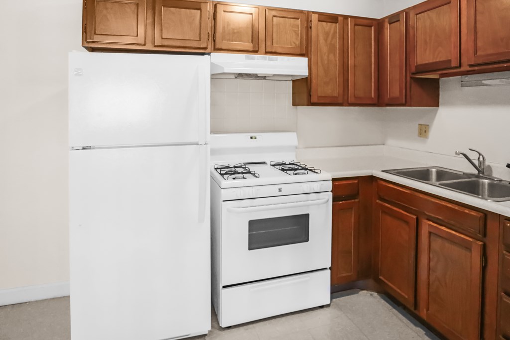 A white refrigerator and stove in a kitchen with brown cabinets.