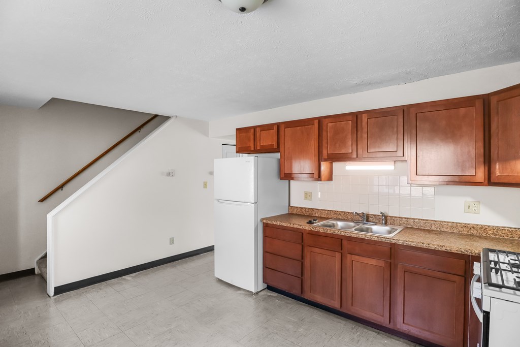 A kitchen with brown cabinets and a white refrigerator.