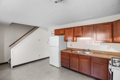 A kitchen with brown cabinets and a white refrigerator.