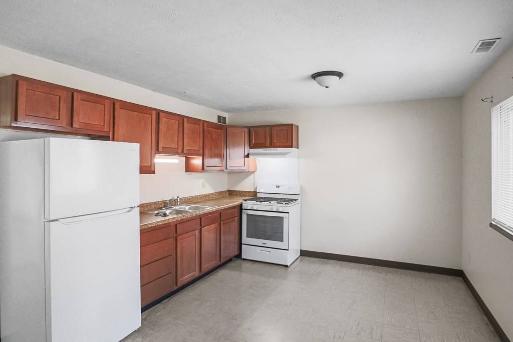 A kitchen with white appliances and brown cabinets.
