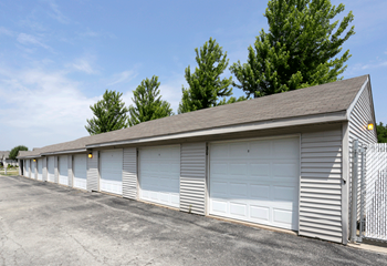 a row of garages with a fence and trees in the background