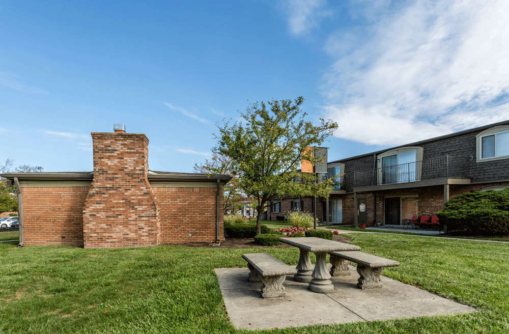 a picnic area with a stone bench in front of a brick building