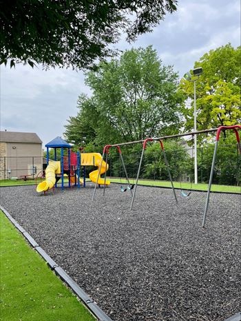 A playground with a yellow slide and a blue canopy.