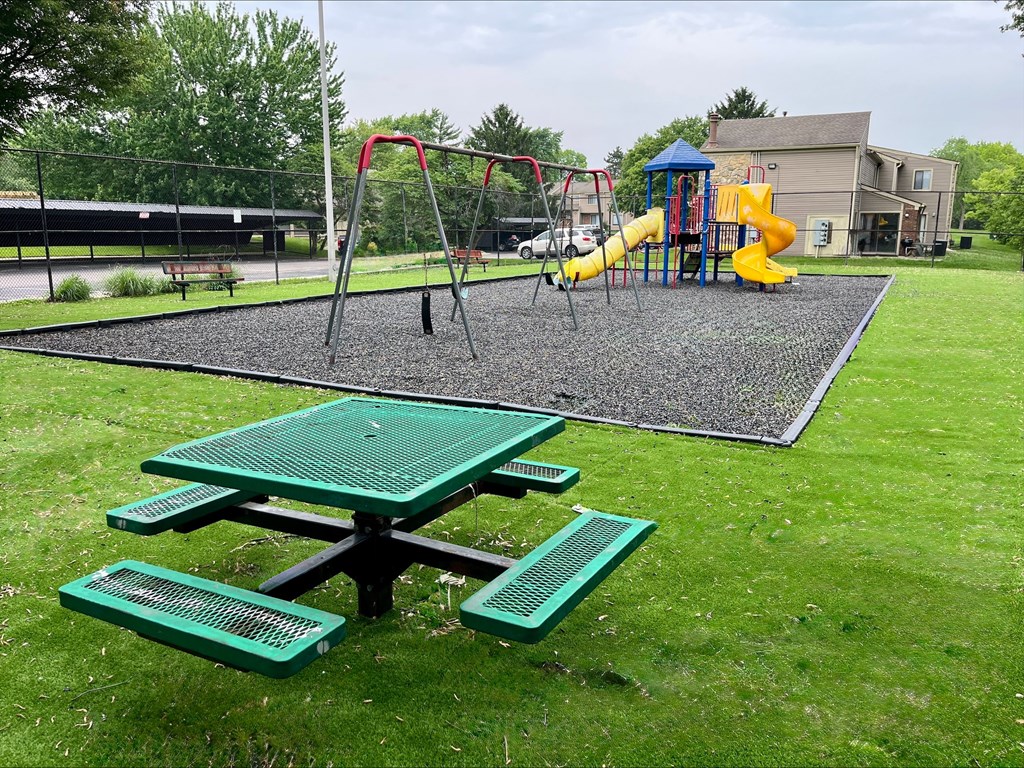 A playground with a green picnic table and a yellow slide.