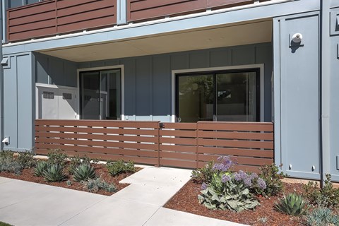 A modern house with a grey front door and a wooden fence.