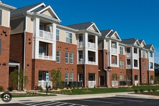 A row of red brick apartment buildings with white trim and balconies.