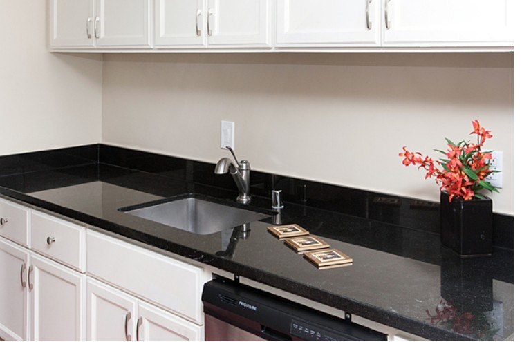 A kitchen with black countertops and white cabinets.