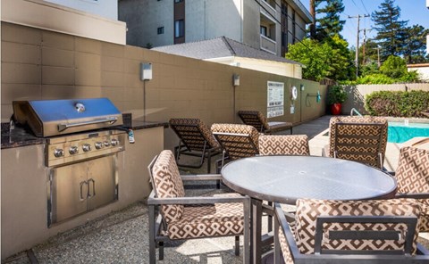 A patio with a table, chairs, and a grill.