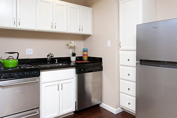 A kitchen with white cabinets and a black countertop.