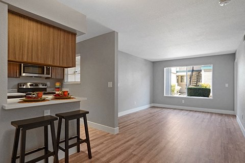 an empty living room with a kitchen and a window