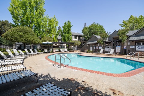 Resort style swimming pool surrounded by lounge chairs at Clayton Creek Apartments, Concord, California
