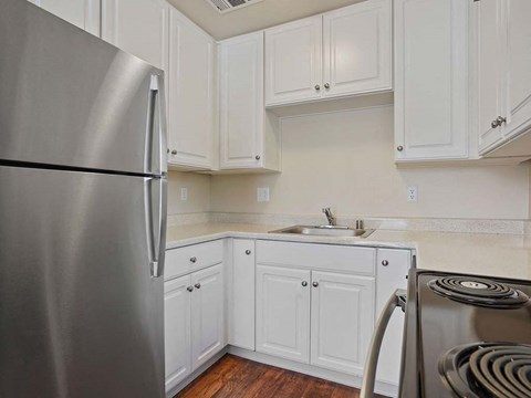a kitchen with white cabinets and a stainless steel refrigerator