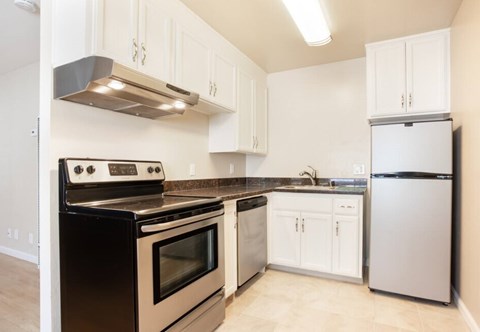 A kitchen with a black stove top oven and white cabinets.