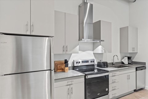 A modern kitchen with stainless steel appliances and white cabinets. at Paperbox Lofts, Salt Lake City, UT, 84101
