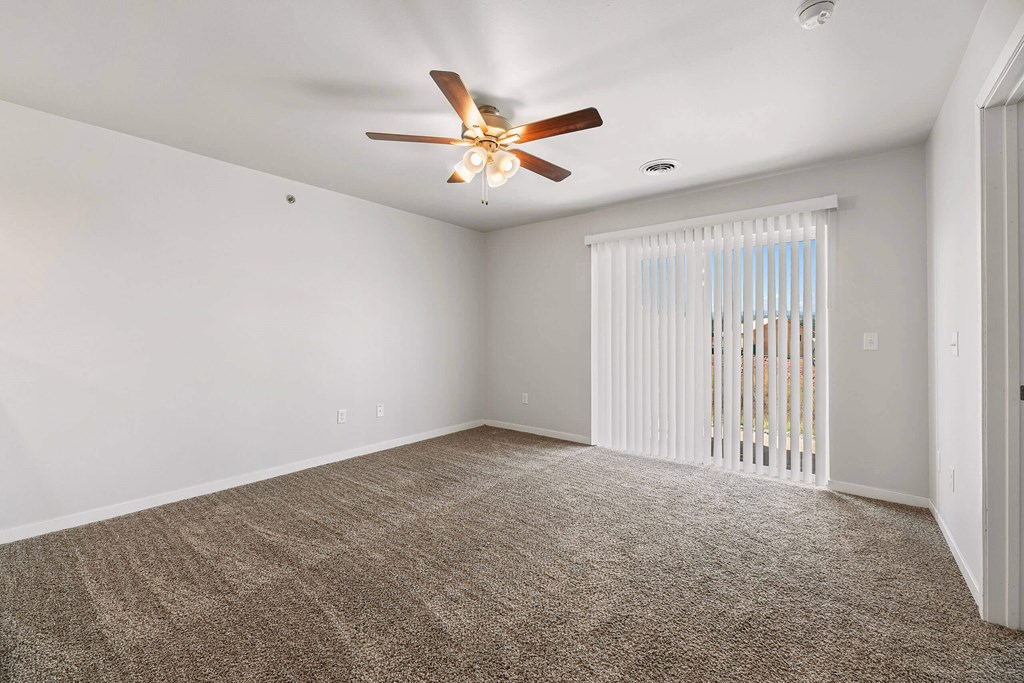 an empty living room with a ceiling fan and a window at Red Rock Apartments, Rapid City, SD