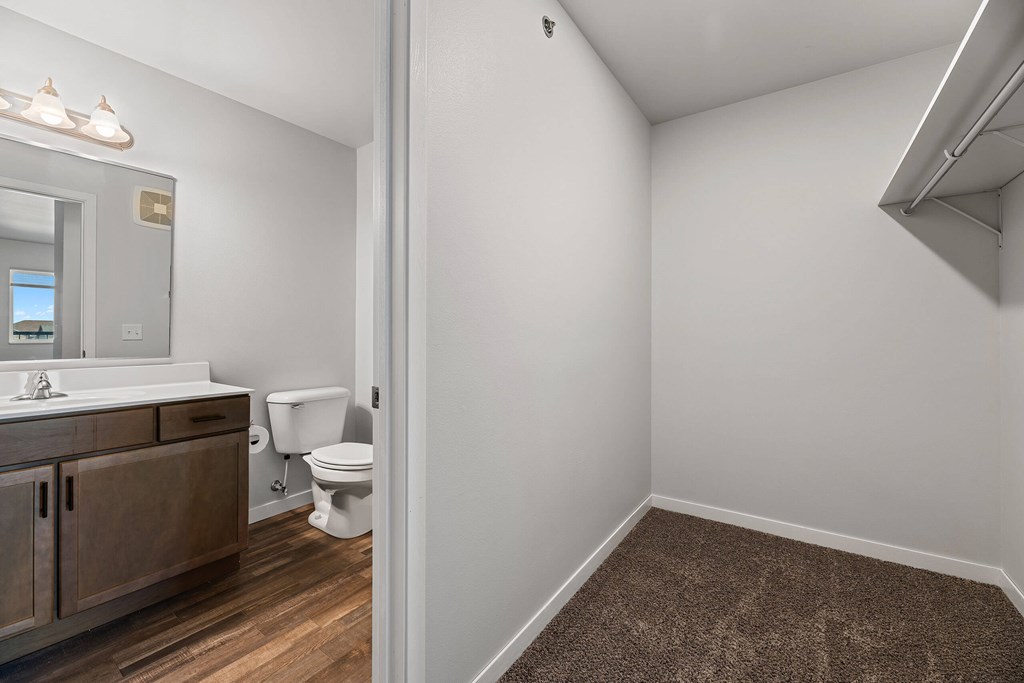 A bathroom with a toilet, sink, and mirror. at Red Rock Apartments, Rapid City, SD, 57702