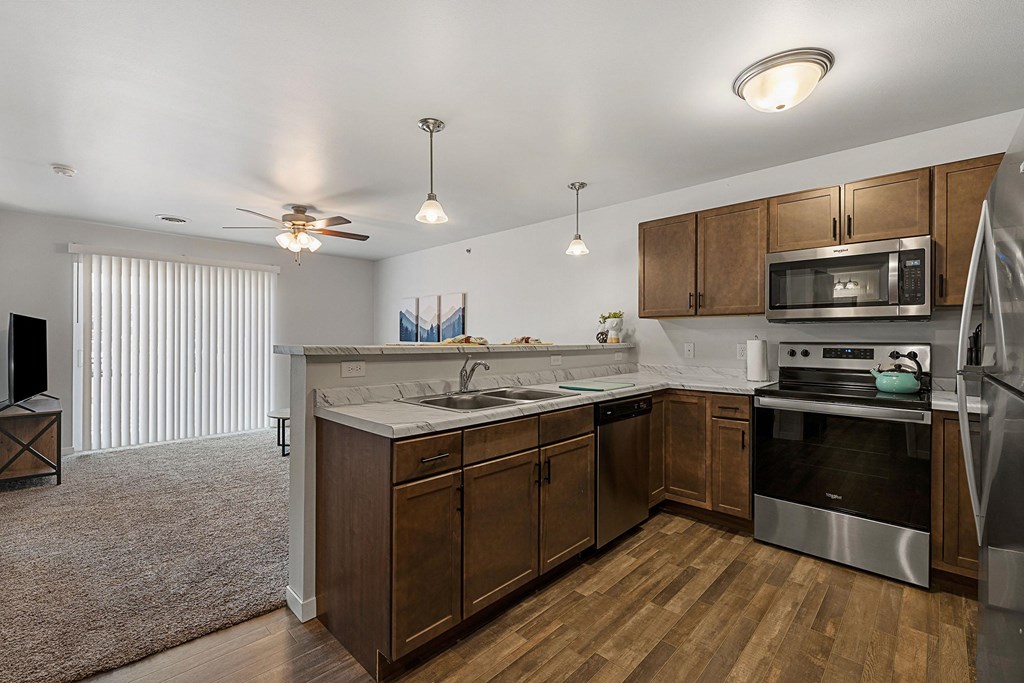 a kitchen with wooden cabinets and stainless steel appliances at Red Rock Apartments, Rapid City, SD