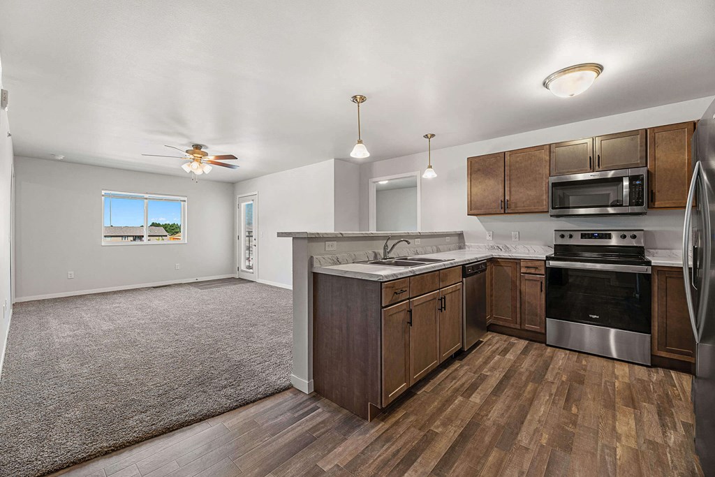 a kitchen with wooden cabinets and stainless steel appliances at Red Rock Apartments, Rapid City, SD, 57702
