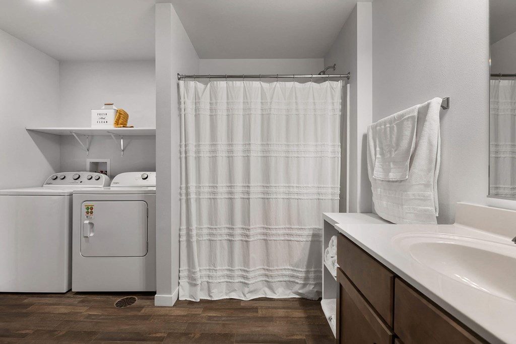 a washer and dryer in a bathroom with a shower and a sink at Red Rock Apartments, South Dakota