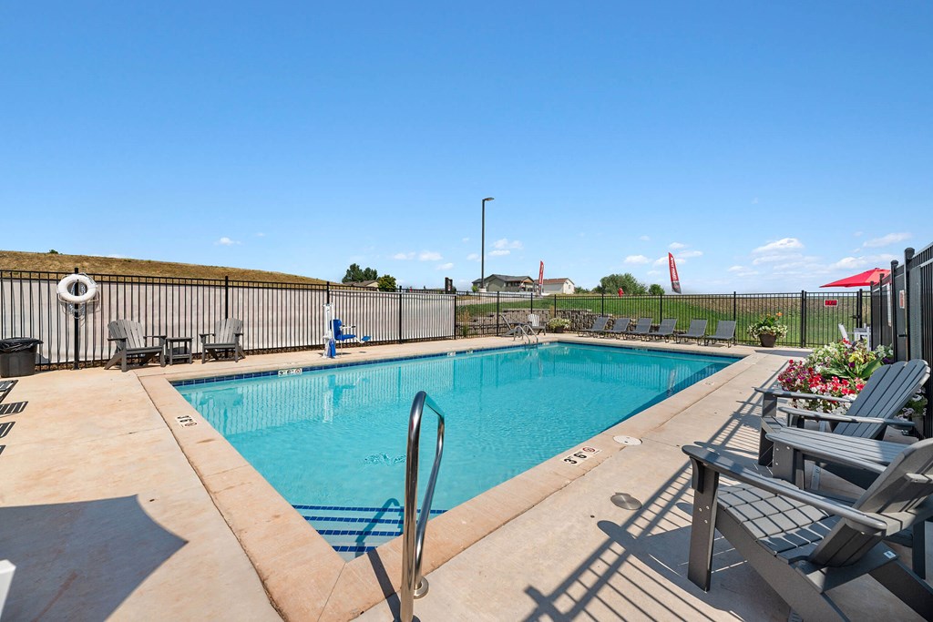 a swimming pool with chairs and a fence around it at Red Rock Apartments, South Dakota 57702