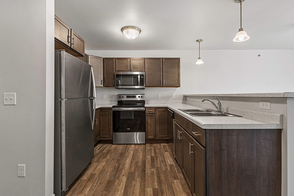 an empty kitchen with stainless steel appliances and wooden cabinets at Red Rock Apartments, Rapid City