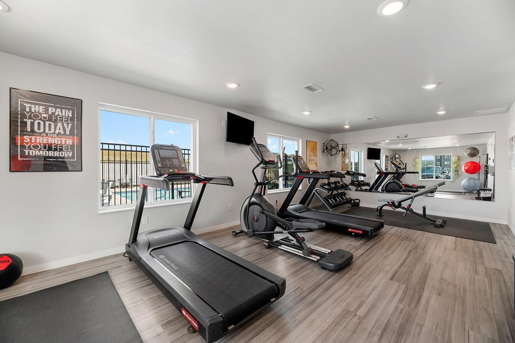 two treadmills and other exercise equipment in a gym with windows at Red Rock Apartments, Rapid City