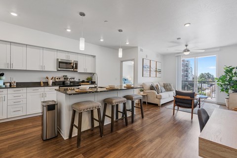 A modern kitchen with white cabinets and a wooden floor.
